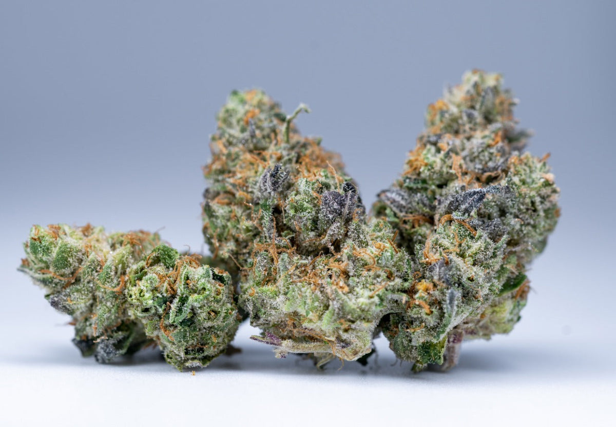 Cogollos de cannabis con tricomas cristalinos sobre fondo neutro