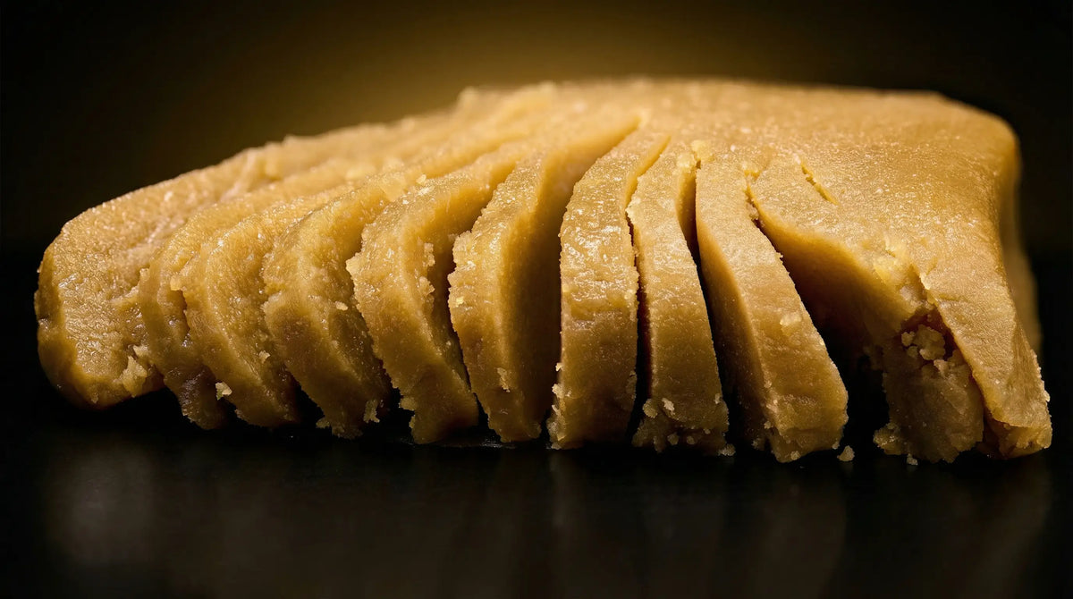 Bloque de hachís dorado cortado en lonchas con textura granulada sobre fondo oscuro