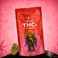 Flores Canapuff THCv Papaya Punch 50%, bolsa de 1 gramo sobre fondo rosa